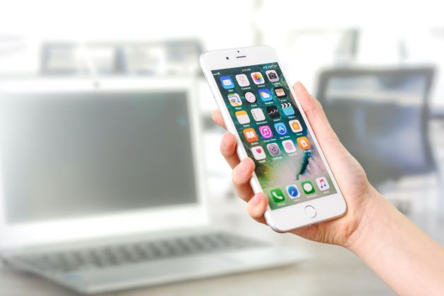 Someone looking at phone in front of laptop